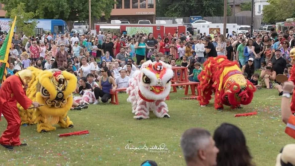 Three colorful lion dancers performing outdoors for a community crowd